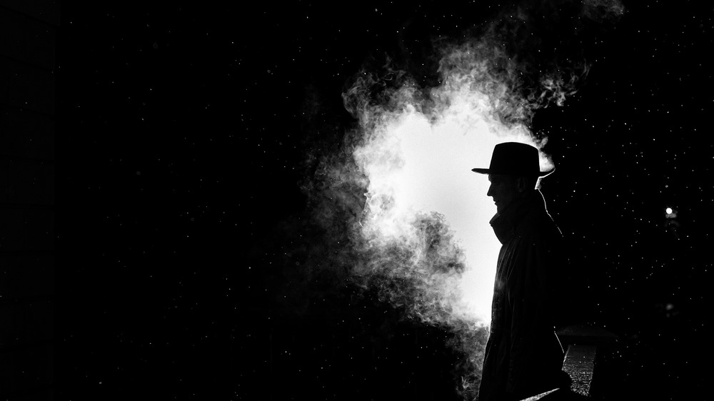 A man in darkness, in front of smoke