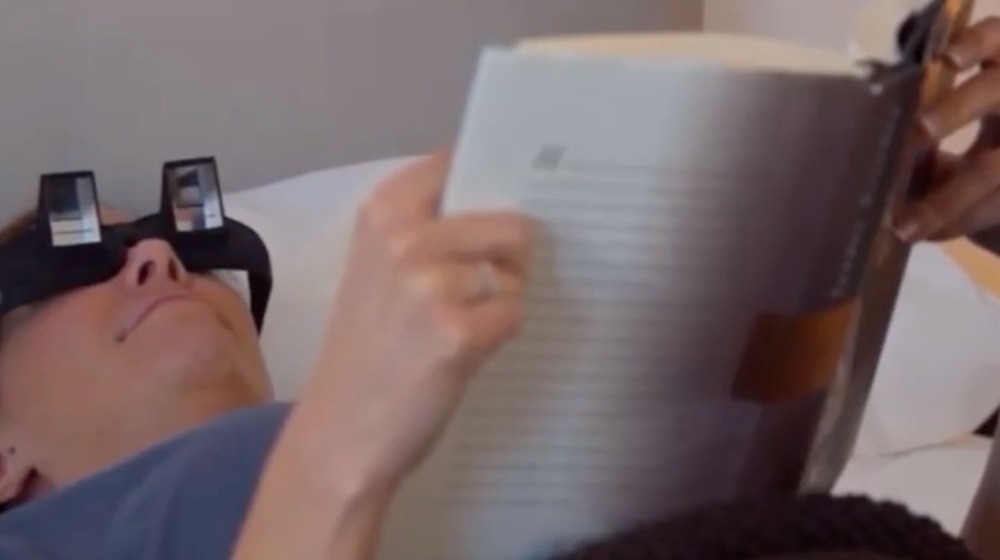 A woman laying on bed wearing lazy readers
