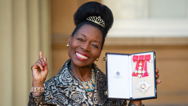 Floella Benjamin smiling with her Damehood medal