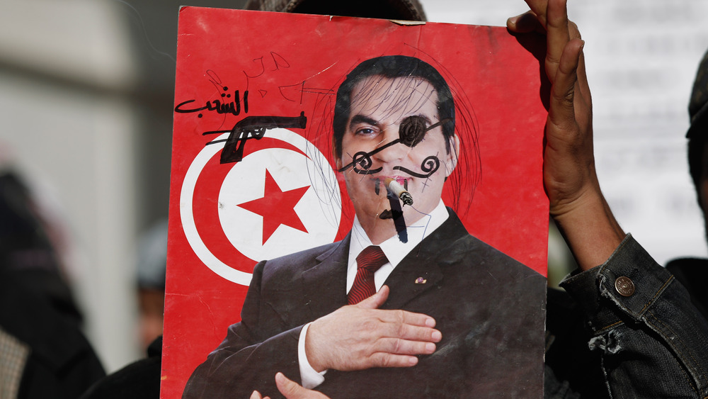 A protestor holds up defaced photo of Zine El Abidine Ben Ali 