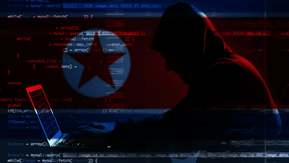 Spooky hacker in shadows behind a North Korean flag