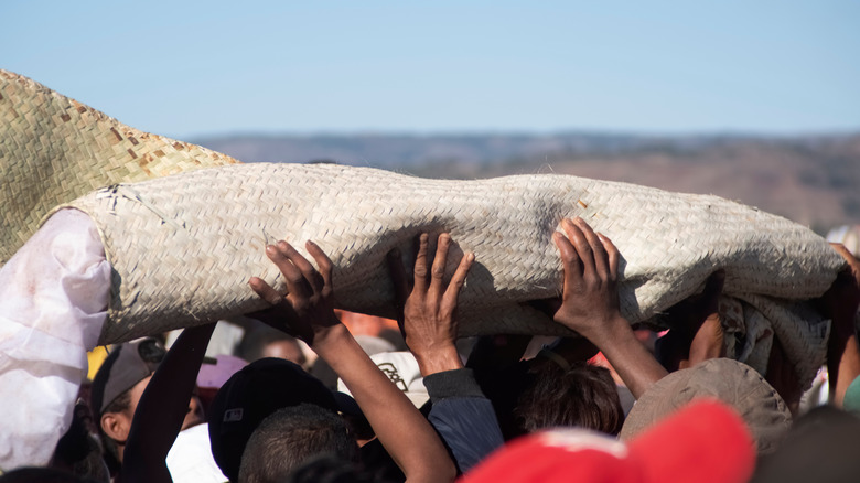 hands carrying body in sack