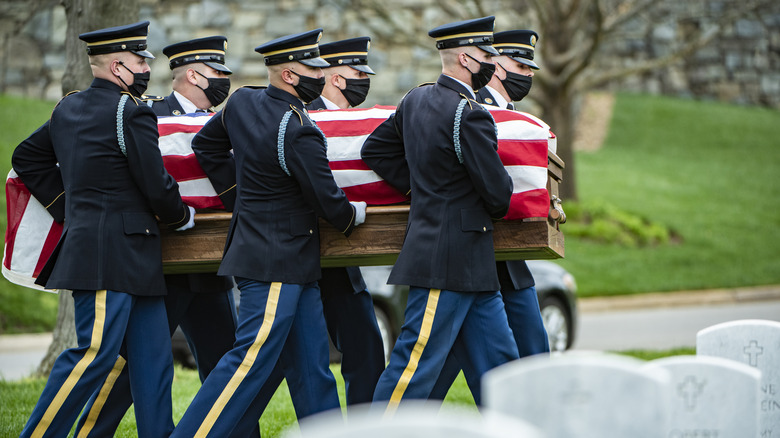 Military pallbearers holding coffin