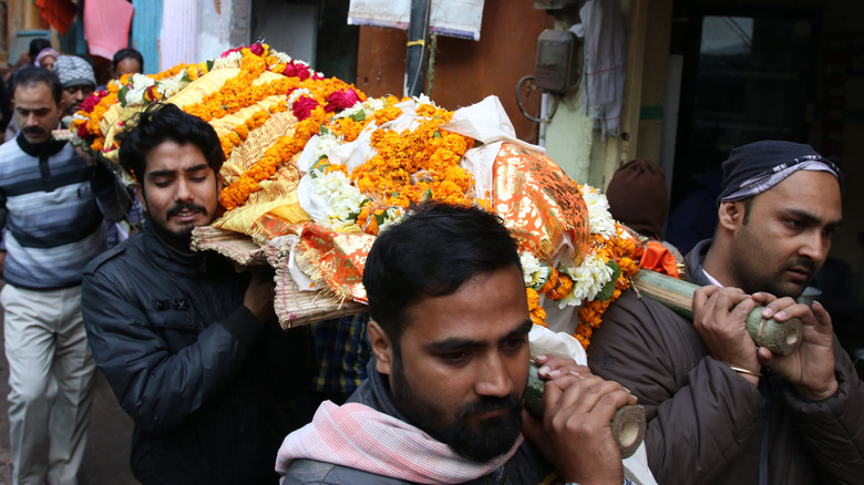 Hinduism pallbearers carrying body covered in flowers