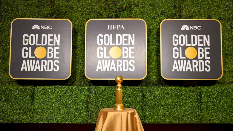 Golden Globe award underneath sign