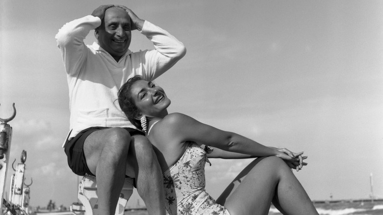 Maria Callas and Giovanni Battista Menghini smiling on a beach