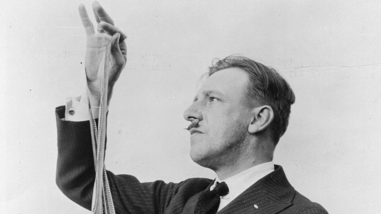 A publicity still of director Tod Browning inspecting the frames of a film