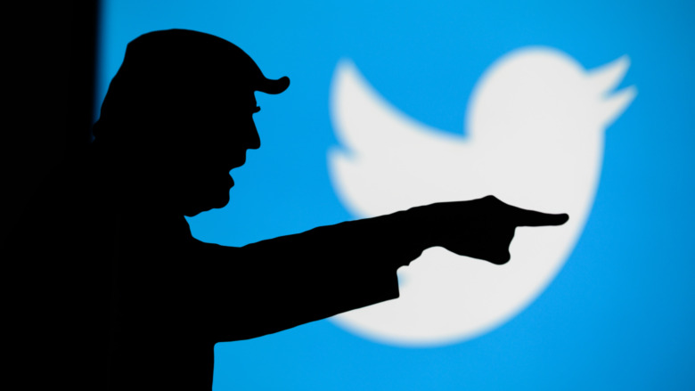 Silhouette of Donald Trump pointing angrily in front of a Twitter logo 