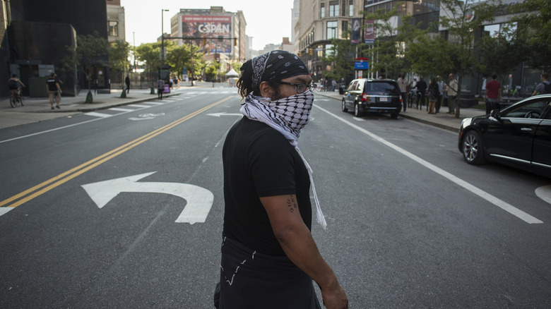 man walking across street wearing mask