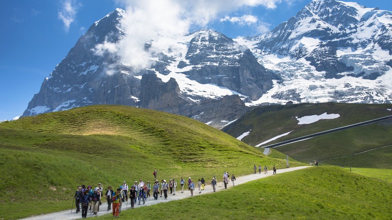 tourists on walking trail by the North Face of the Eiger mountain in the Swiss Alps, Bernese Oberland, Switzerland
