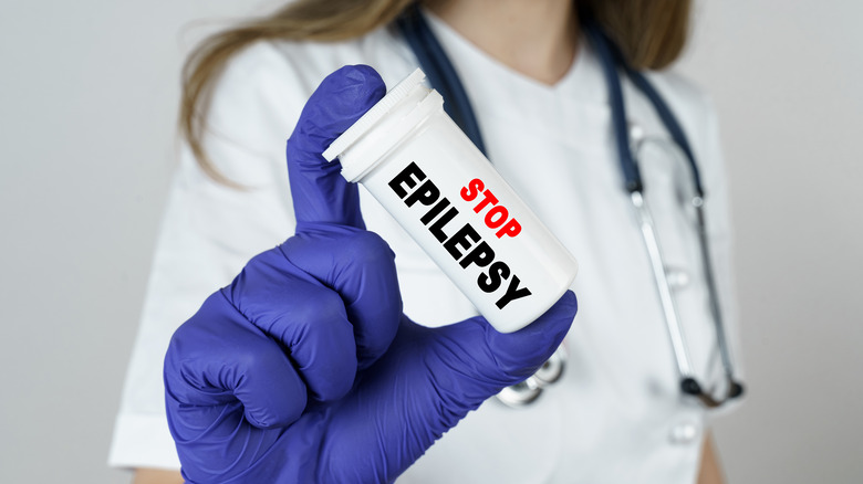 gloved hand holding Stop Epilepsy bottle