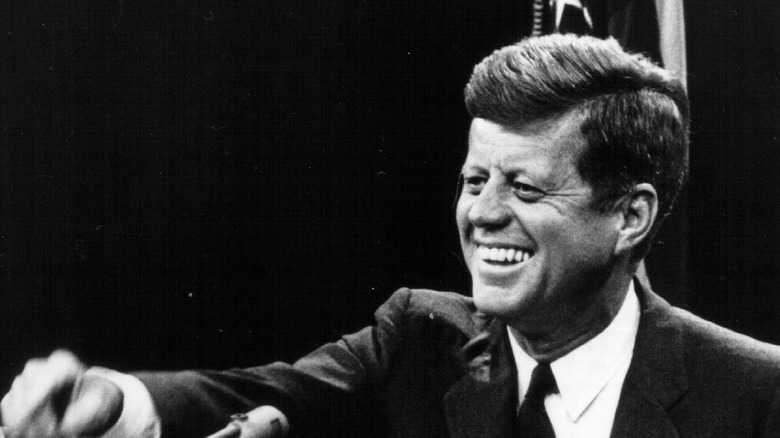 JFK smiling at podium