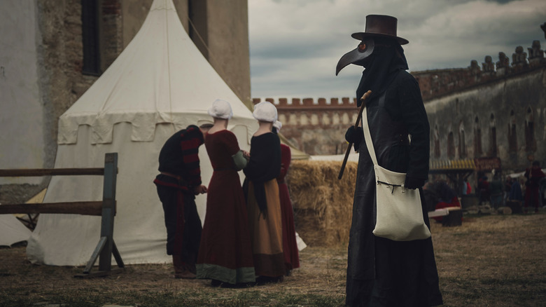 Plague doctor enters medieval town 