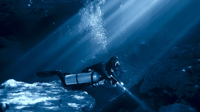 Underwater diver with flashlight in lightbeam