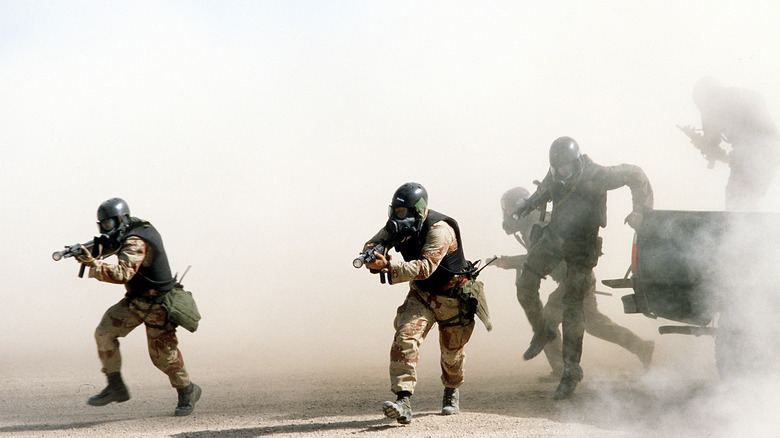 U.S. Navy Sea-Air-Land (SEAL) team members wearing chemical-biological masks train in the Southern California desert.