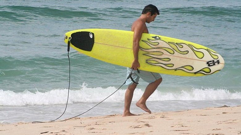 Man carrying surfboard on beach
