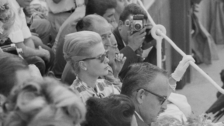 Grace Kelly and Prince Rainier III seated in a crowd