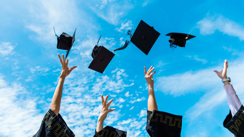 Graduates toss mortarboards in the air