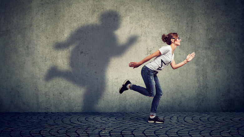 Woman running with larger shadow