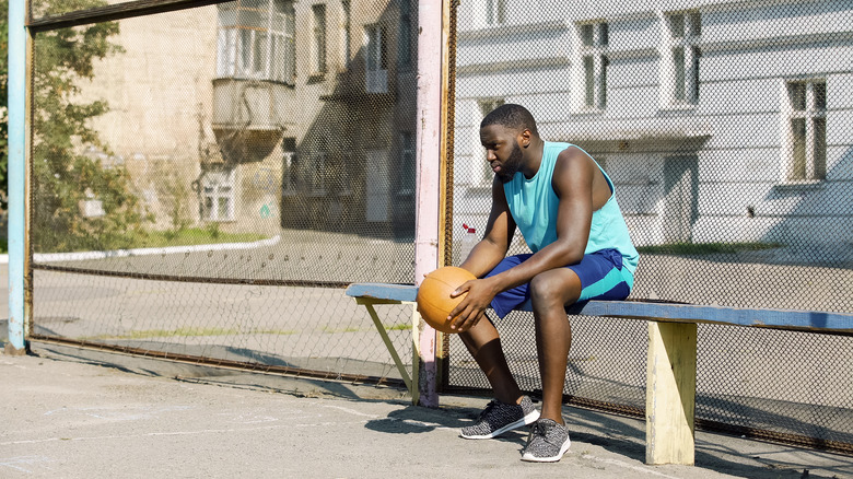 Man with basketball sitting on bench