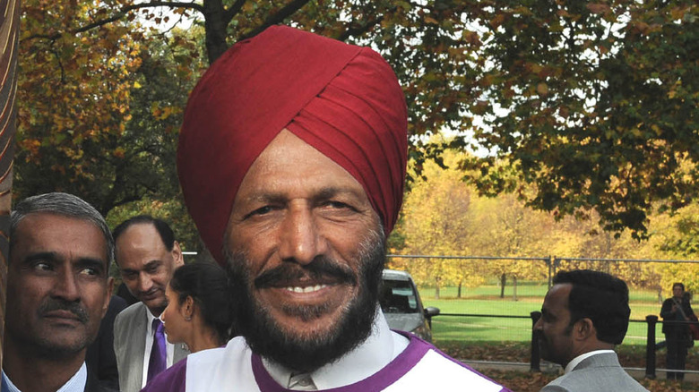 Milkha Singh smiling with people behind him
