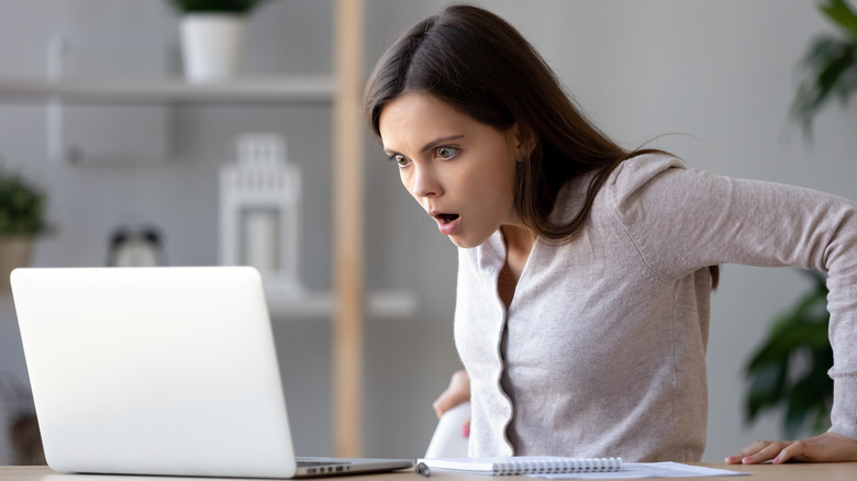 Scared woman looking at laptop