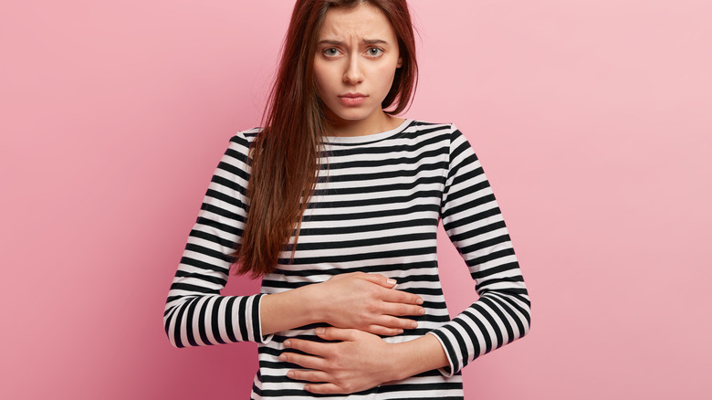 Woman in striped shirt holding her stomach