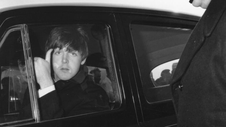 Paul McCartney giving thumb's up while driving car