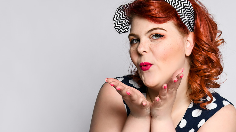 Red headed pinup model blowing kiss