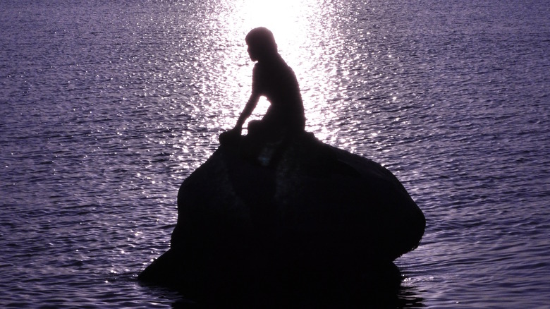 silhouette of mermaid on rock