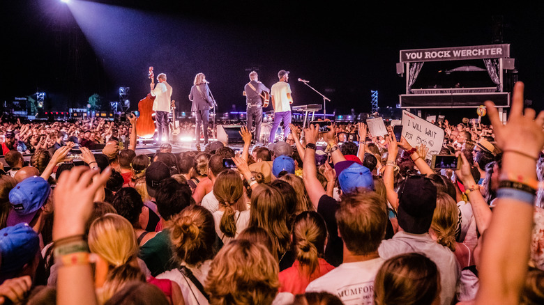 Mumford & Sons at a concert surrounded by fans