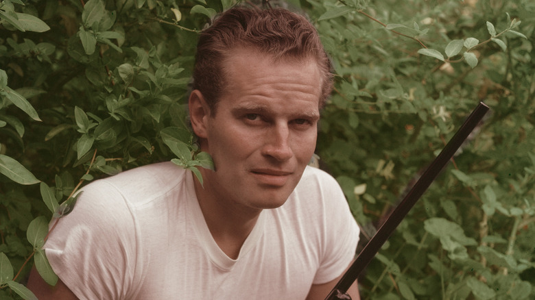 Heston in the bushes, armed