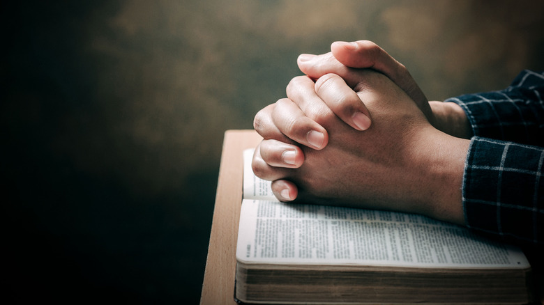 Hands clasped in prayer over Bible