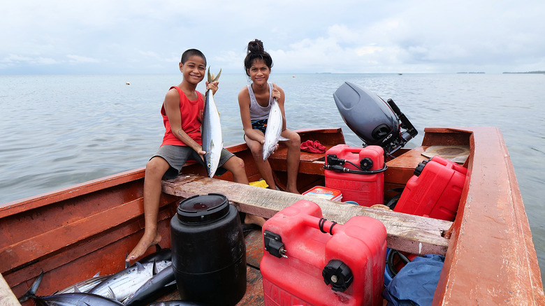 Tuvalu boy and girl in boat with fish