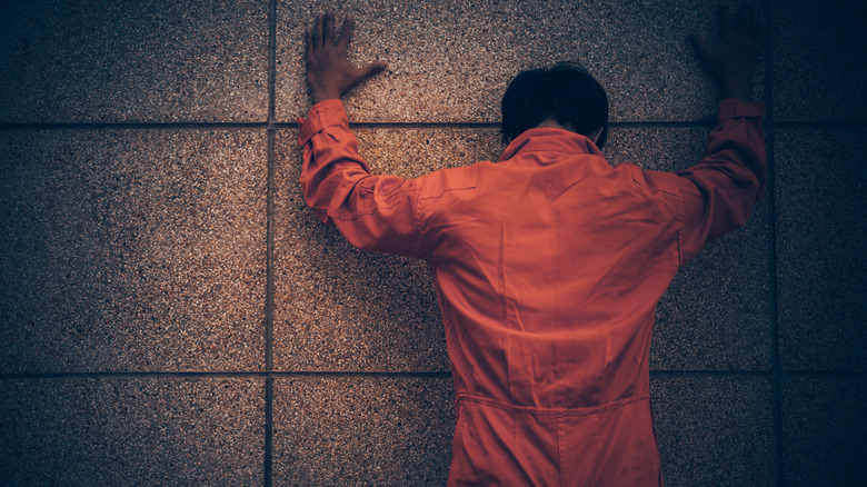 Prisoner with hands against the wall