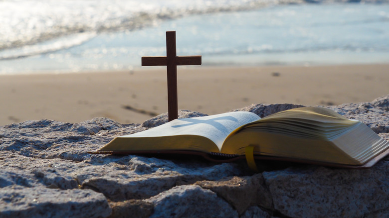 the bible and a cross on a beach