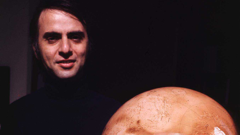 Carl Sagan holding a model of mars
