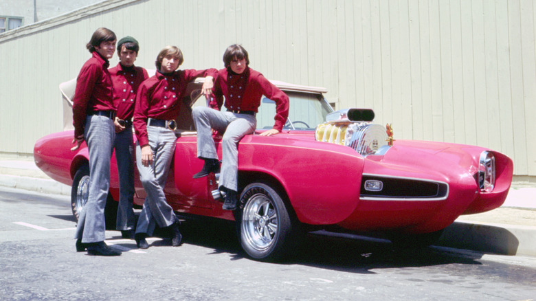 The Monkees posing with the Monkee Mobile