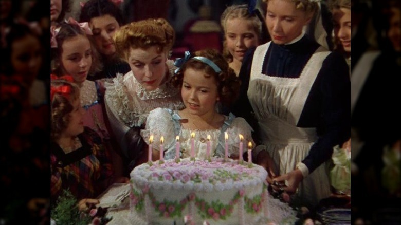 Shirley Temple seated in front of birthday cake
