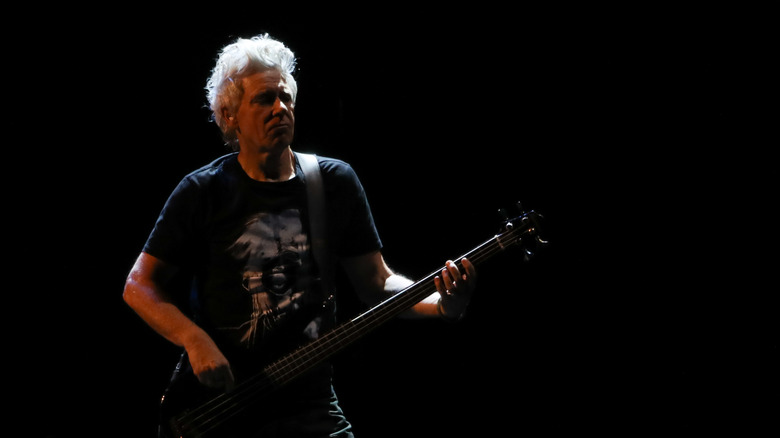 Adam Clayton on stage with guitar