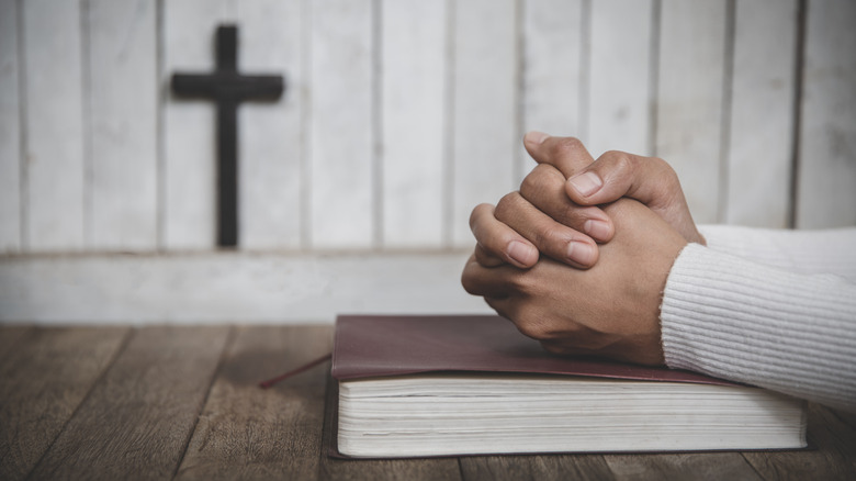 folded hands atop a bible