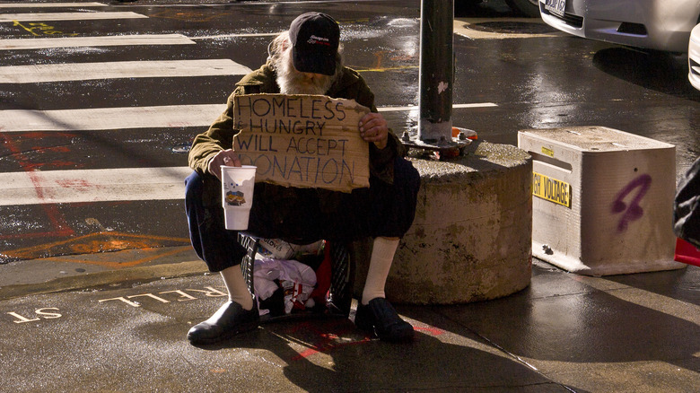 Homeless man holding sign and cup