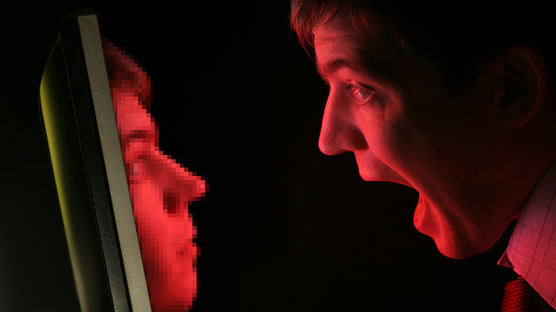 Man with mouth open looking at pixelated version of himself coming from computer