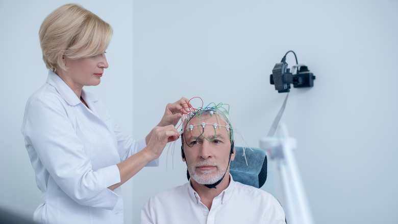 A neurologist prepares a man for an EEG