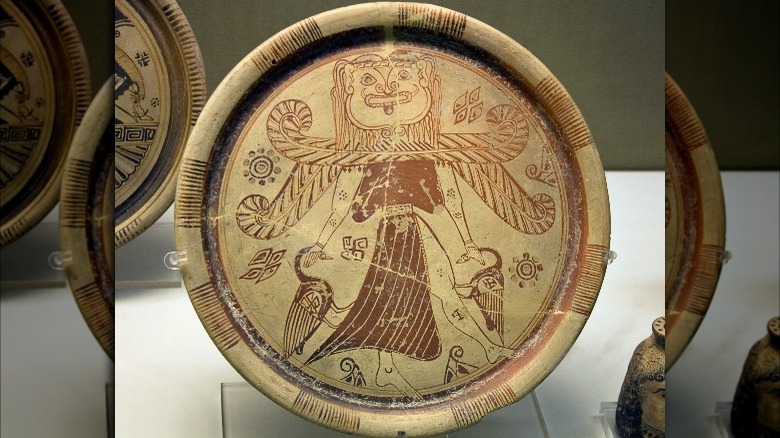 Winged goddess with a Gorgon's head wearing a split skirt and holding a bird in each hand