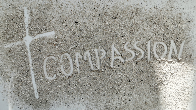compassion with cross written in the sand