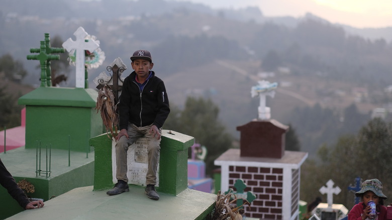 Guatemalan boy sits in cemetery