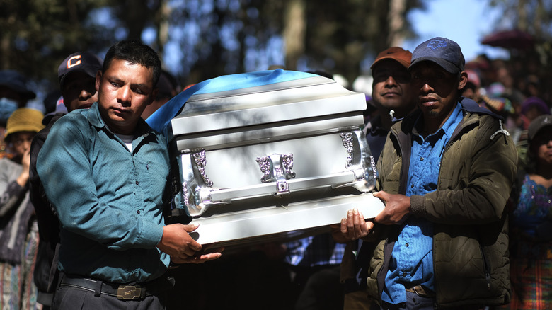 Two men carry a coffin