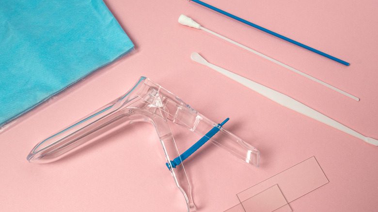Gynecological speculum and swabs on pink table