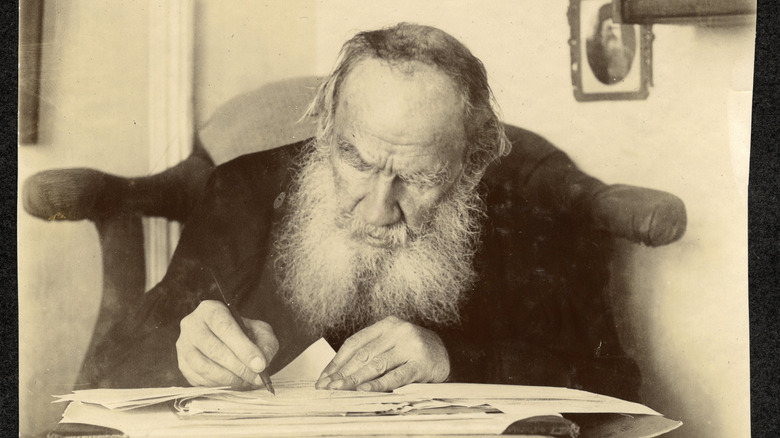 Leo Tolstoy working at a small table